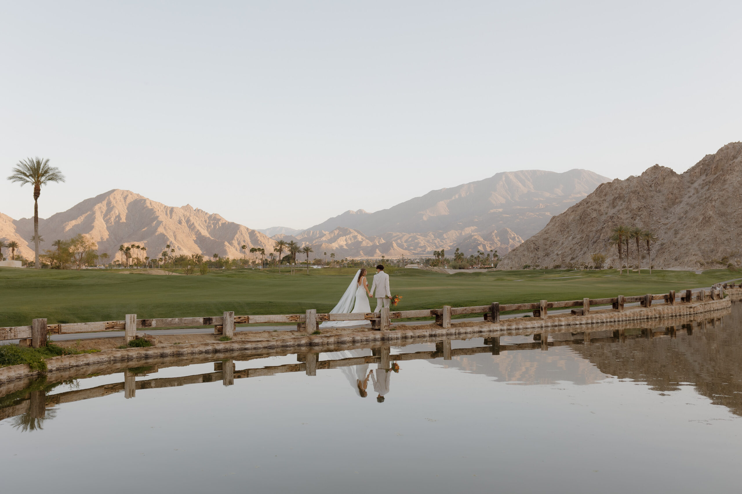 bride and groom walking at venue PGA West in Palm Springs with desert mountains in background