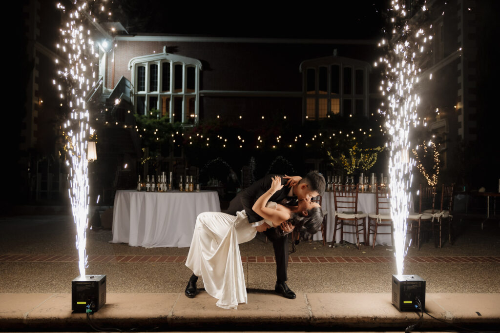 wedding couple kissing in the middle of cold sparklers with mansion in background